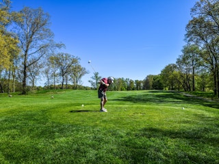 Man golfing on green grass.