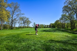 Man golfing on green grass.