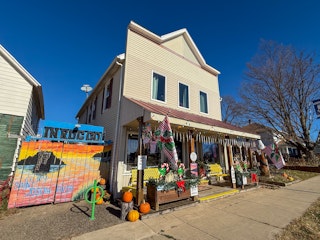 InRugCo. Studio & Gift Shop charming store front with festive decorations, colorful banners, and a b…