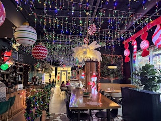 A festive decorated bar with bright ornaments, fairy lights, and holiday-themed decor, creating a ch…