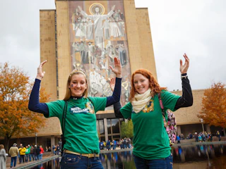 Two girls pose in front of Touchdown Jesus