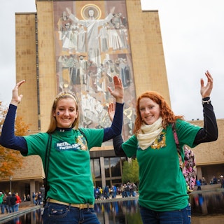 Two girls pose in front of Touchdown Jesus