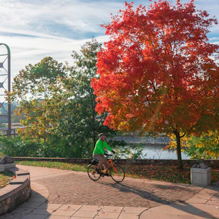 A bicyclist rides along the Mishawaka river walk in Autumn