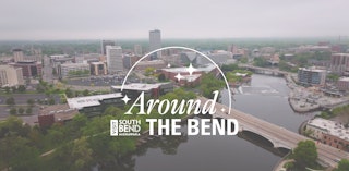 Aerial view of South Bend, Indiana, showcasing skyline, green parks, and rivers with text overlay: "…