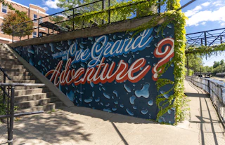 Painted mural along the East Race Waterway that states, "What is life but one grand adventure?"