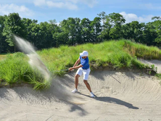 A golfer hit a ball at a grassy golf course