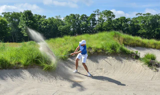 A golfer hit a ball at a grassy golf course